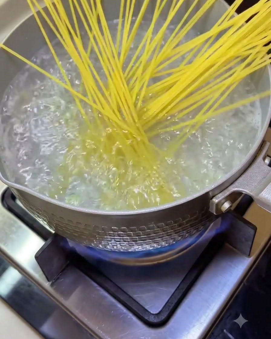 Makaron spaghetti wrzucany do garnka z wrzącą wodą na kuchence.