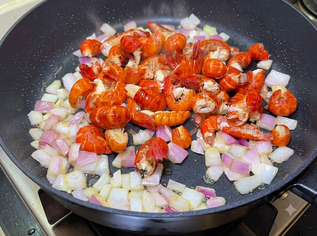 Szyjki rakowe i pokrojona cebula smażone razem na patelni.