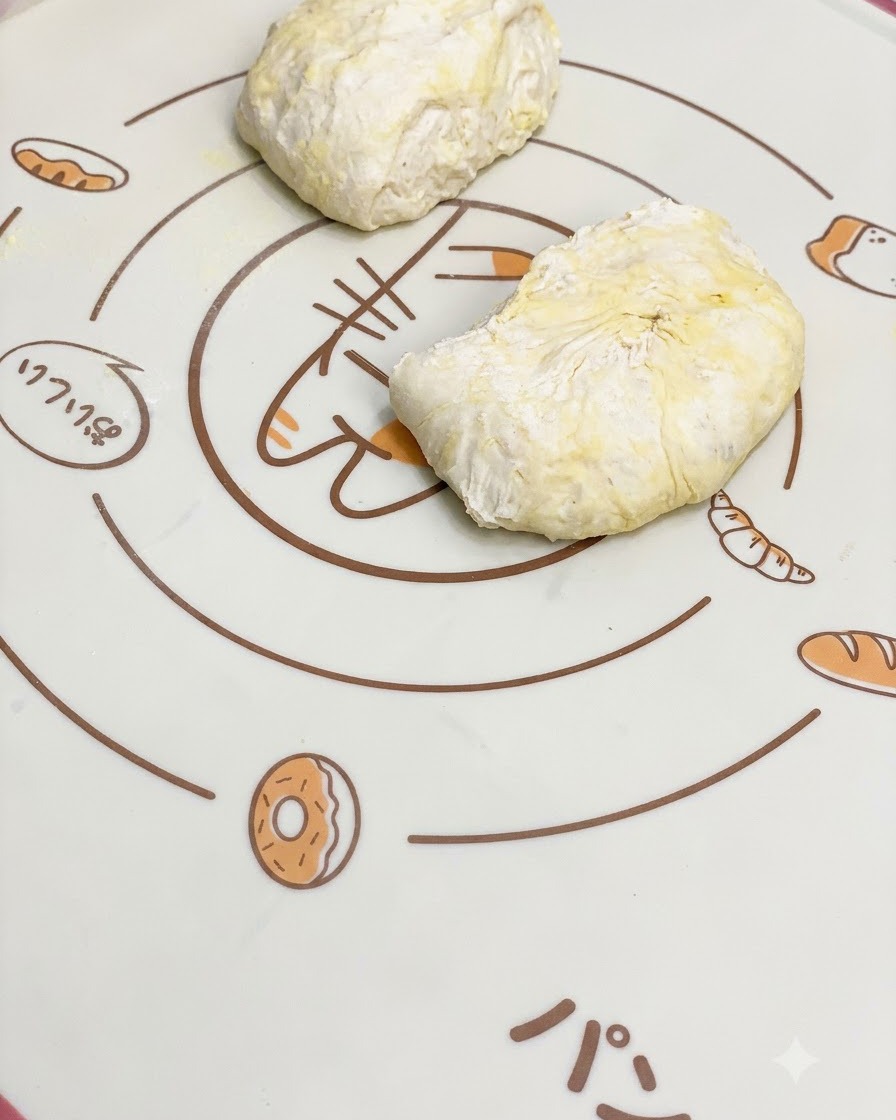 Porcje wyrośniętego ciasta na pizzę odpoczywające na wzorzystej macie silikonowej.
