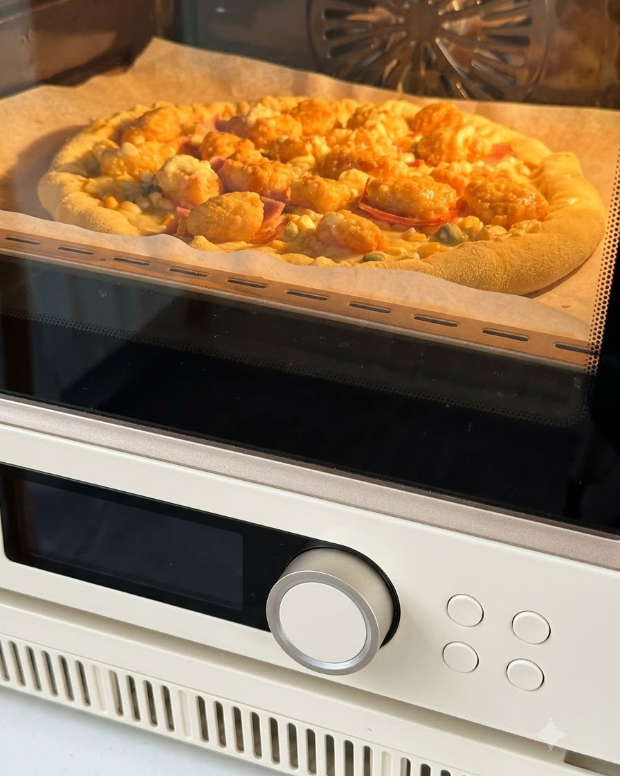 Złożona pizza na papierze do pieczenia wkładana do piekarnika rozgrzanego na ciepły pomarańczowy kolor.