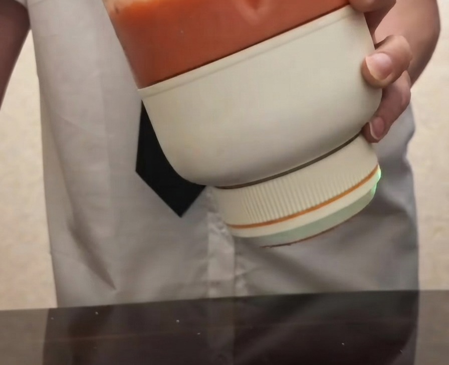 Osoba trzymająca przenośny blender elektryczny wypełniony gładkim, jaskrawoczerwonym puree pomidorowym.