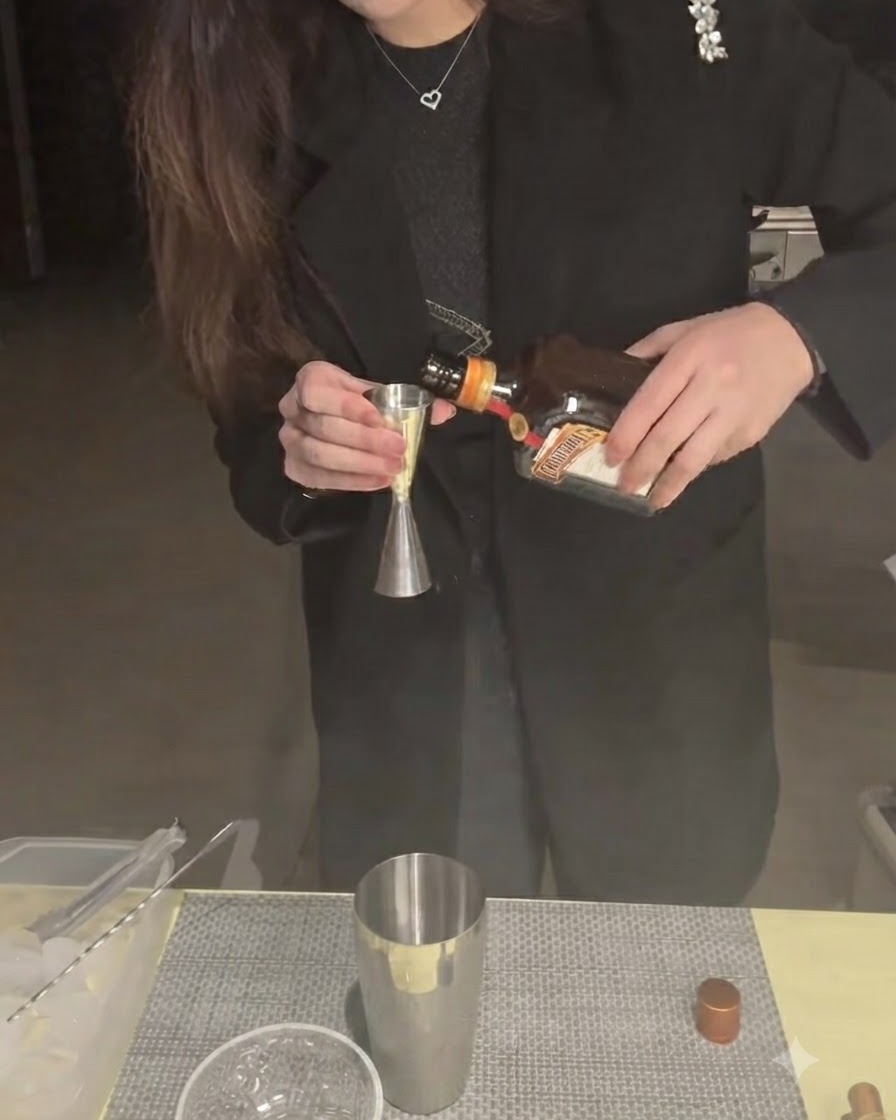 Cointreau nalewane do miarki barmańskiej z dolną częścią shakera w tle.