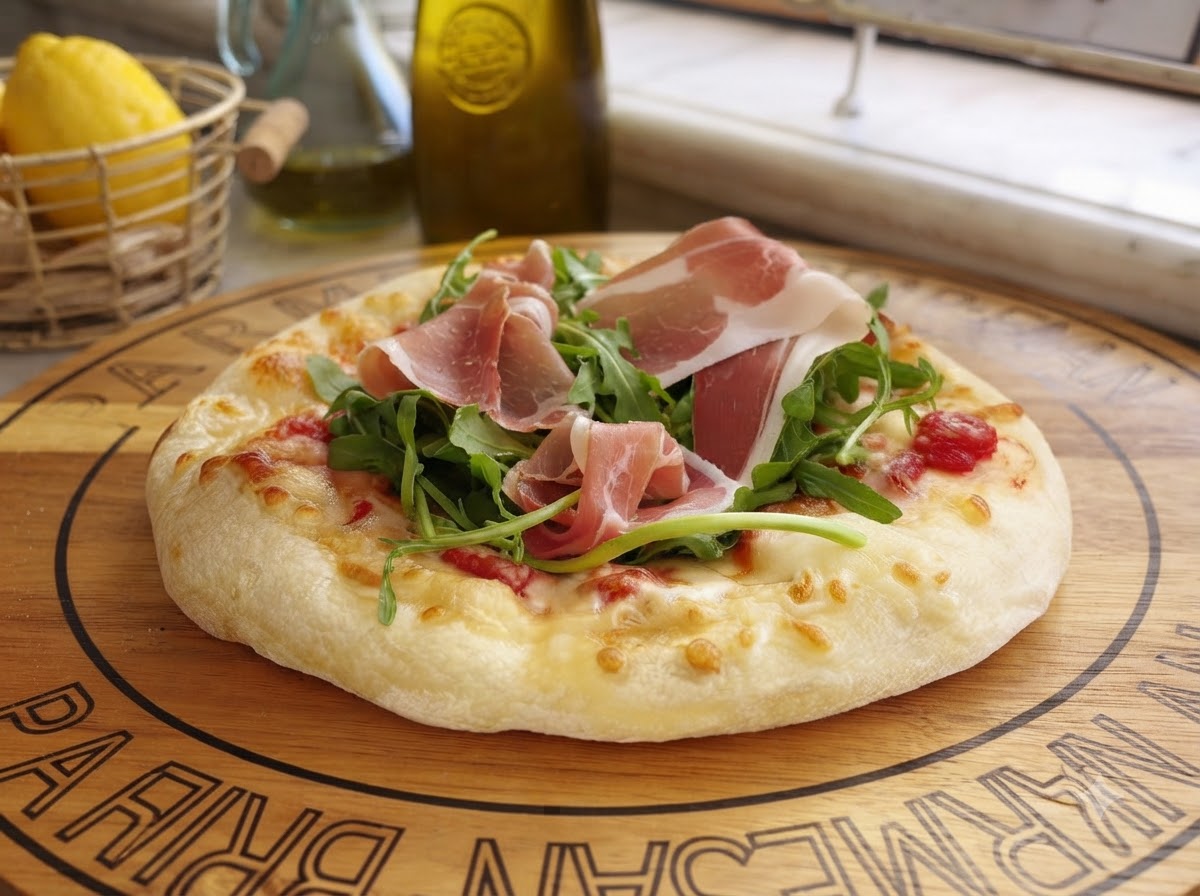 Świeżo starte płatki parmezanu spadające na przygotowaną pizzę z zieleniną i szynką.