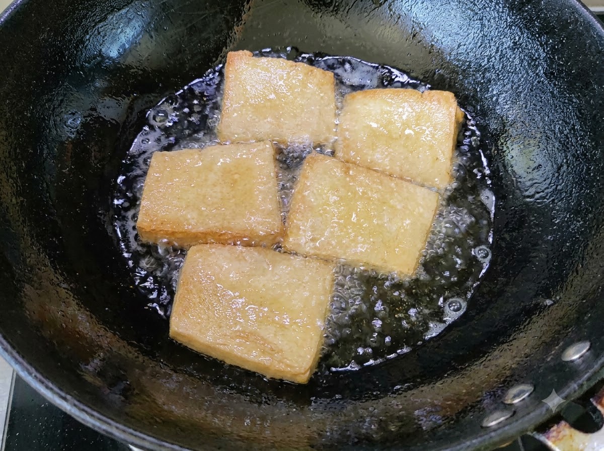Złociste kawałki tofu smażące się w woku w bulgoczącym oleju.