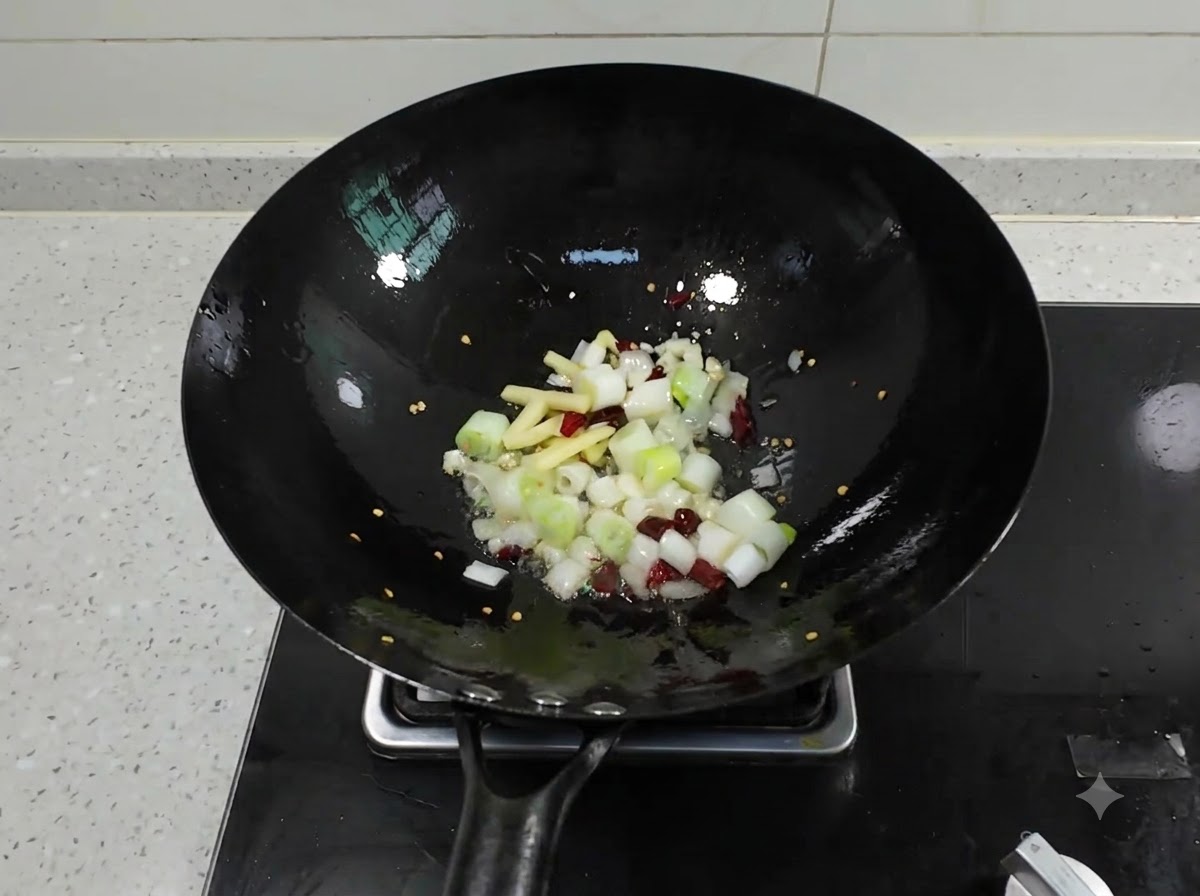 Posiekana zielona cebulka, imbir, czosnek i suszone chili skwierczące w czarnym woku z gorącym olejem.