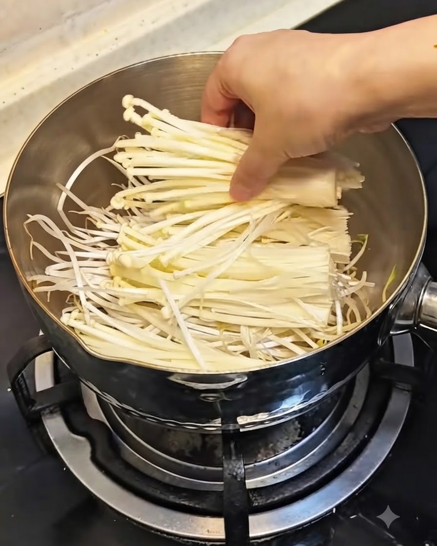 Dłoń układająca pęczek świeżych, białych grzybów enoki na kiełkach fasoli w garnku.