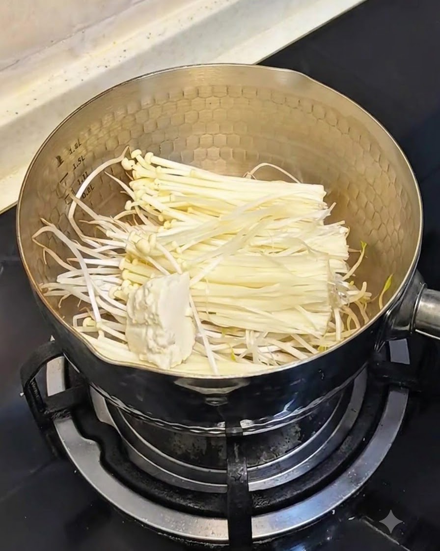 Łyżka miękkiego jedwabistego tofu dodawana do garnka z kiełkami fasoli i grzybami.