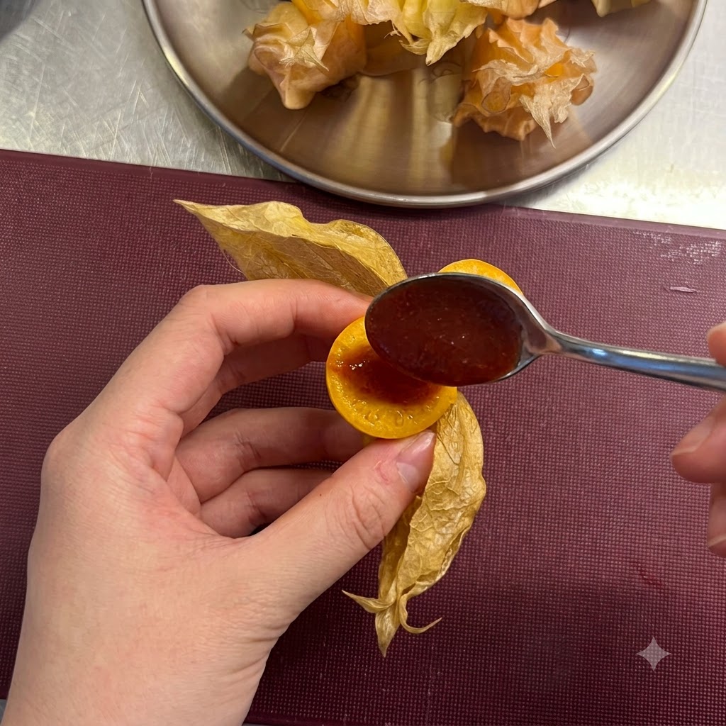 Mała łyżeczka nakładająca odrobinę czerwonego sosu chili do wnętrza naciętej miechunki.