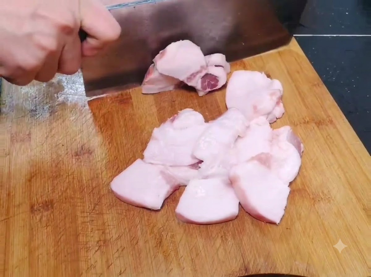 Cienkie, szerokie kawałki surowej wieprzowiny krojone na drewnianej desce do krojenia.