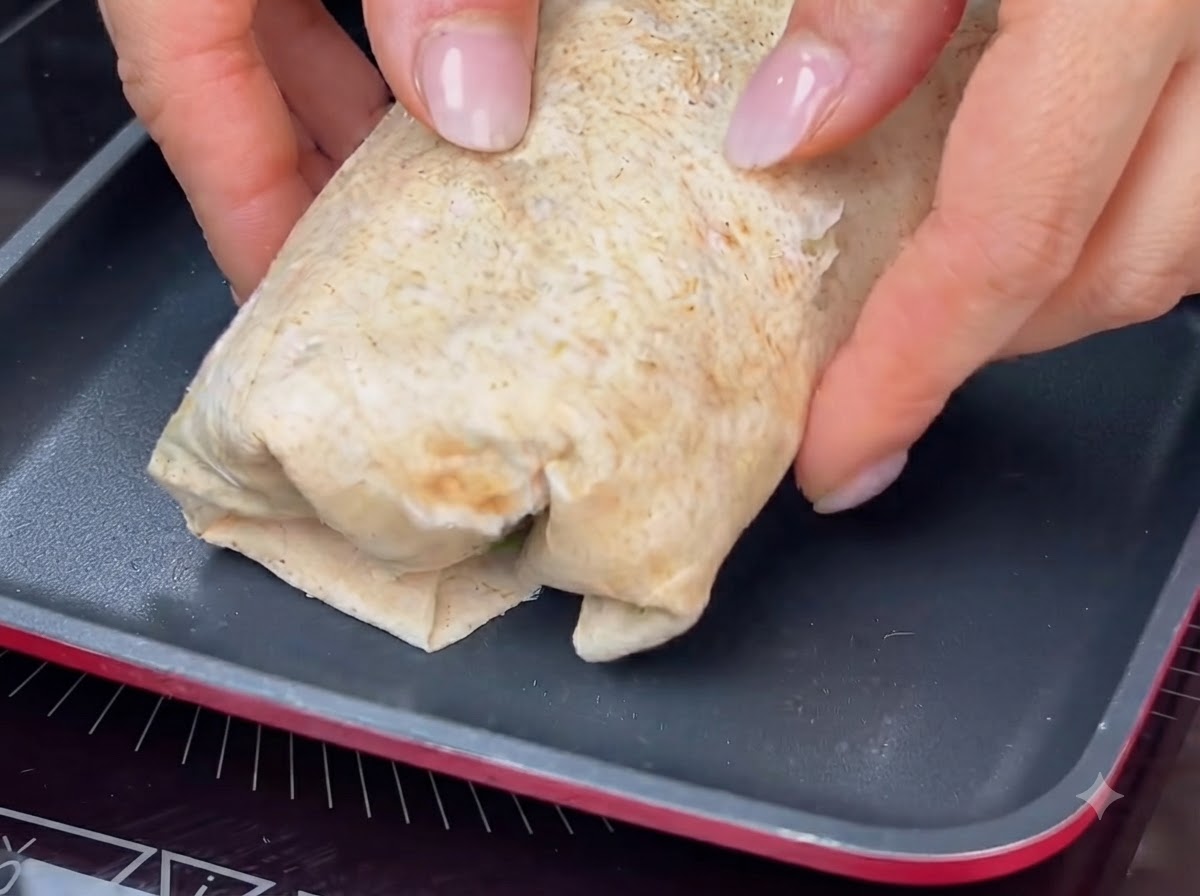 Zwinięty wrap opiekany na gorącej patelni, aby uzyskać złocisto-brązową skórkę.