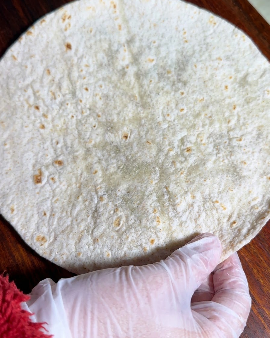 Pełnoziarnista tortilla rozłożona na płasko na drewnianej powierzchni.