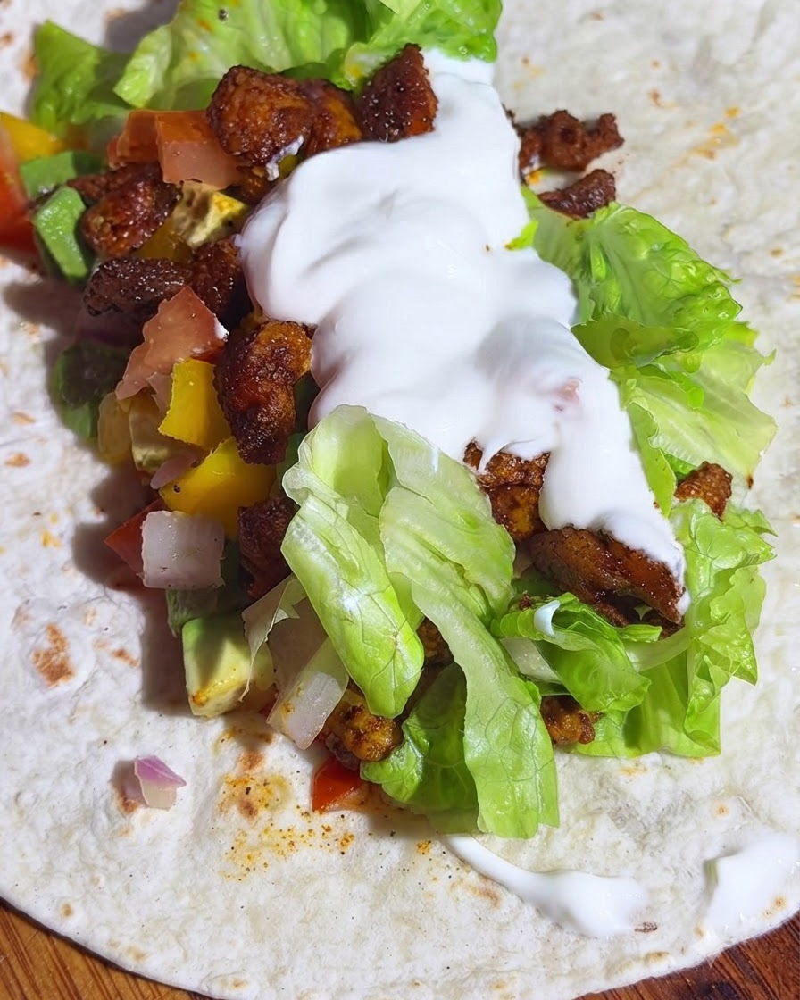 Pełnoziarnista tortilla przełożona sałatą, salsą z awokado, kurczakiem i porcją jogurtu.