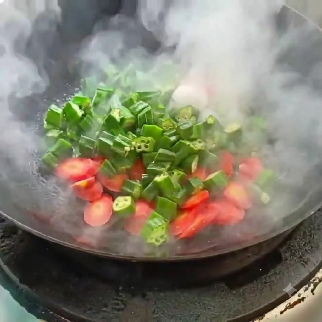 Pokrojona okra i marchewka smażone w gorącym woku z unoszącą się parą.