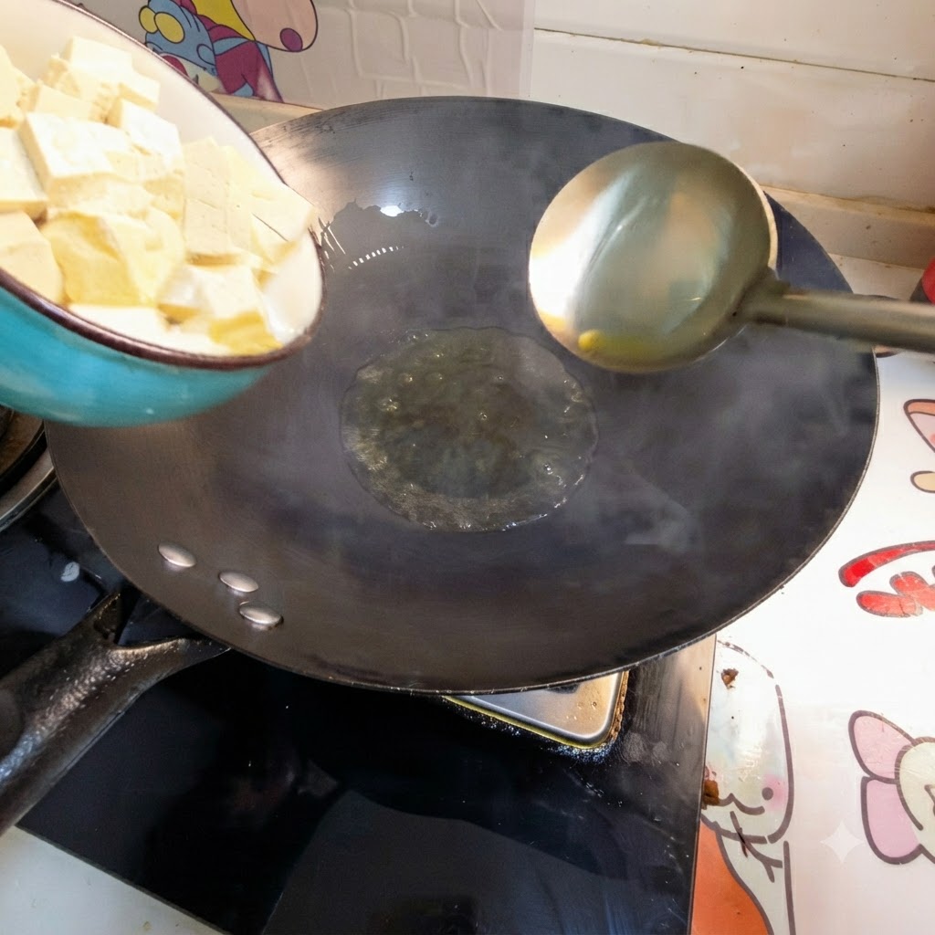 Kostki tofu wsypywane z miski do gorącego oleju na woku.