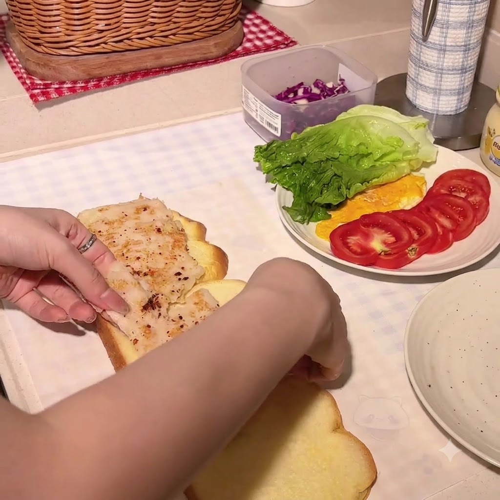 Musztarda miodowa wyciskana na kromkę chleba dyniowego z kotletem z kurczaka.