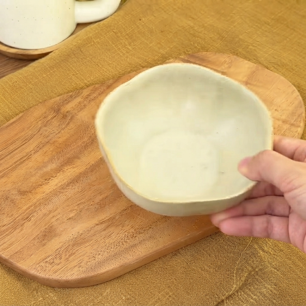 Mała ceramiczna miska na drewnianej desce, gotowa do wymieszania sosu.