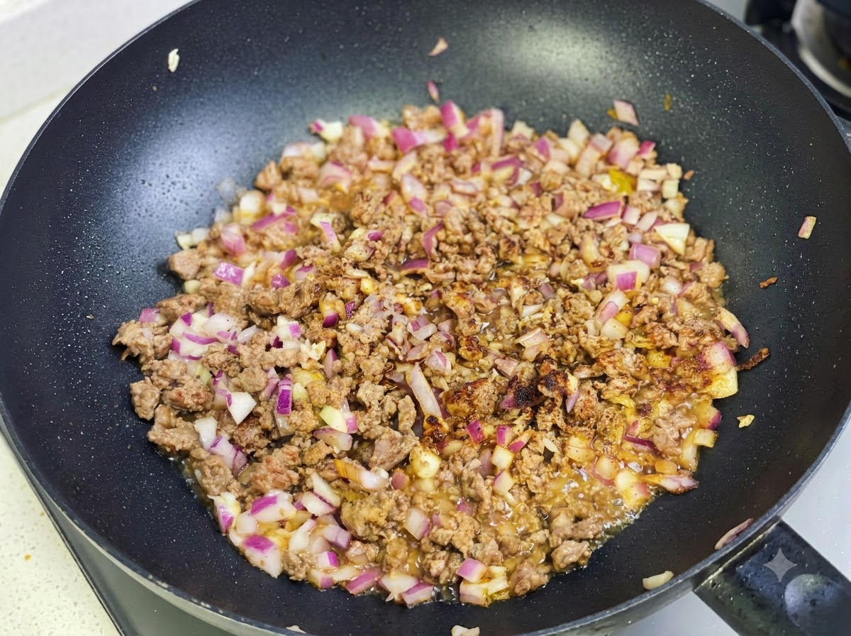 Pasta curry i przyprawy smażone razem z mieszanką mięsa i cebuli na patelni.