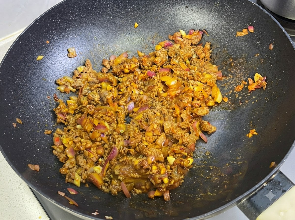 Mleko wlewane do sosu curry z mięsem na patelni.