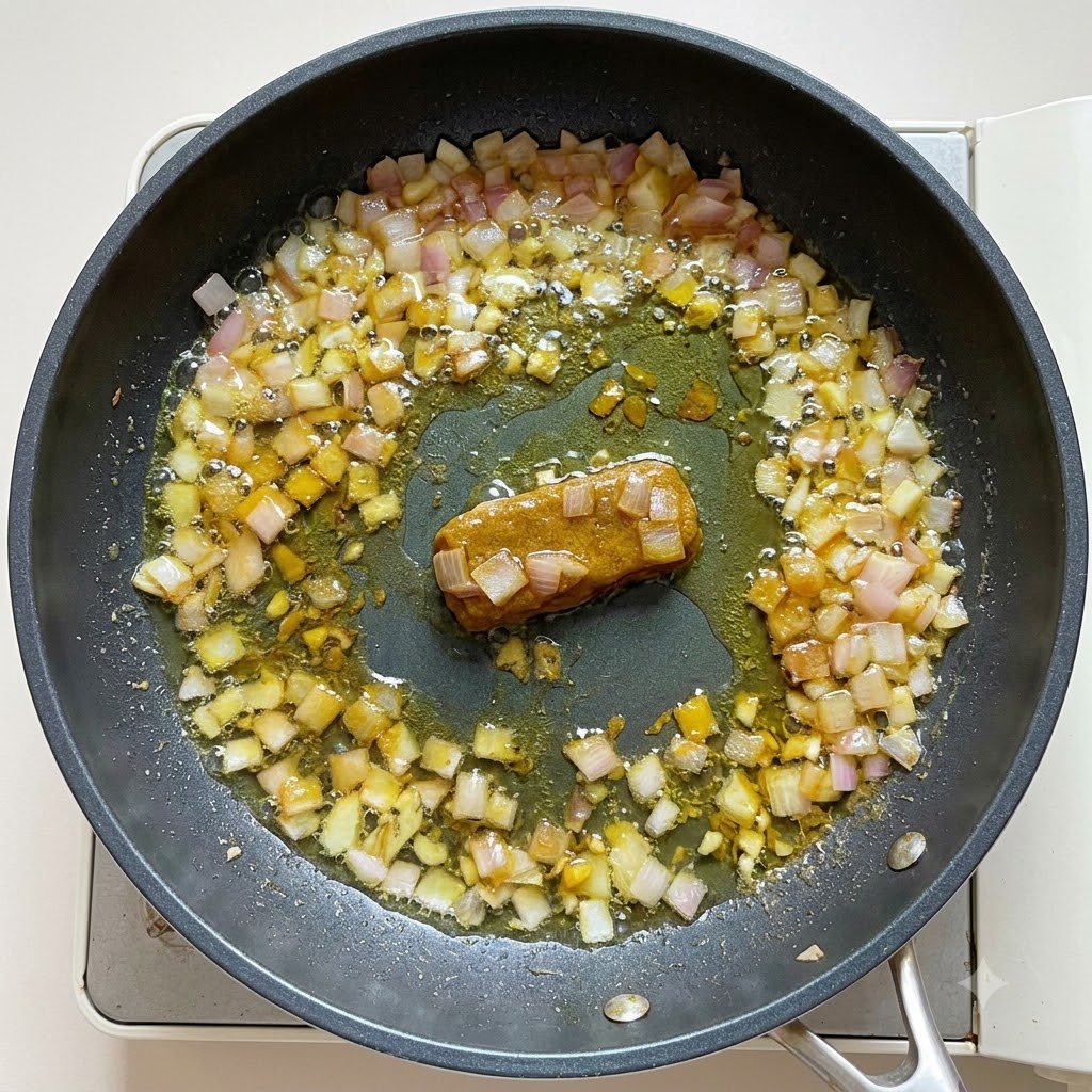Woda i mleko kokosowe wlewane do bazy curry na patelni, mieszane do uzyskania gęstej konsystencji.