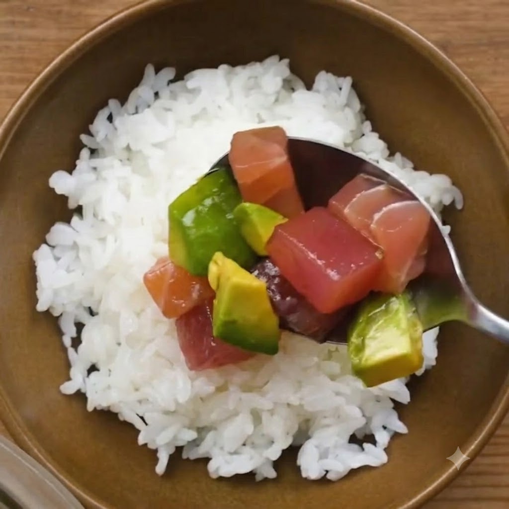 Łyżka marynowanego tuńczyka i awokado umieszczana na misce białego ryżu do sushi.
