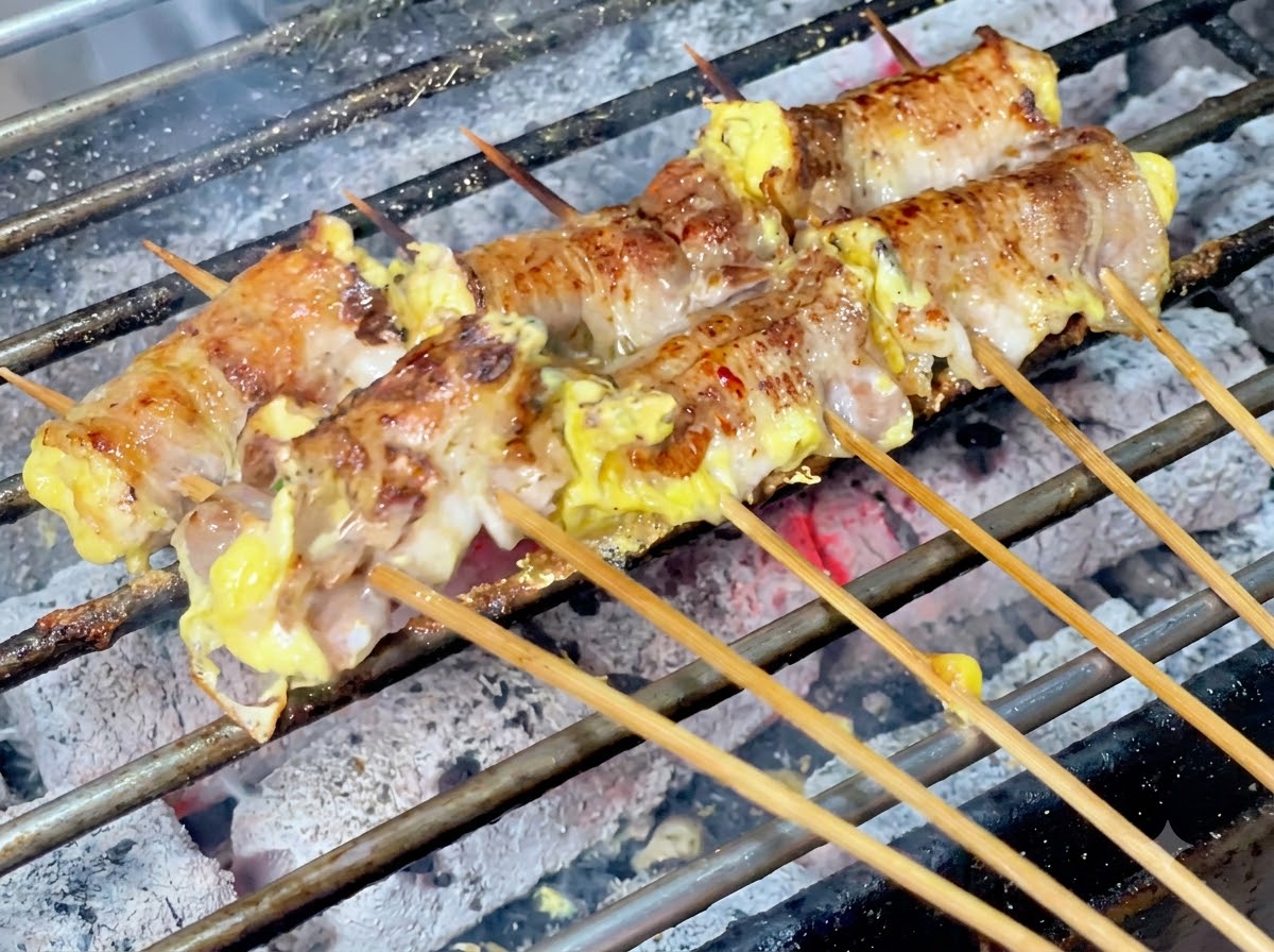 Chili w proszku posypywane na skwierczące roladki mięsne na grillu węglowym.
