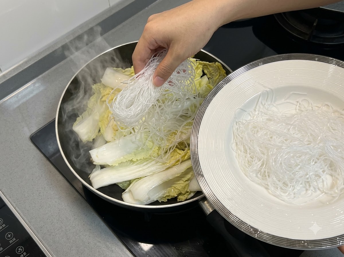 Makaron vermicelli układany na warstwie kapusty chińskiej wewnątrz patelni.