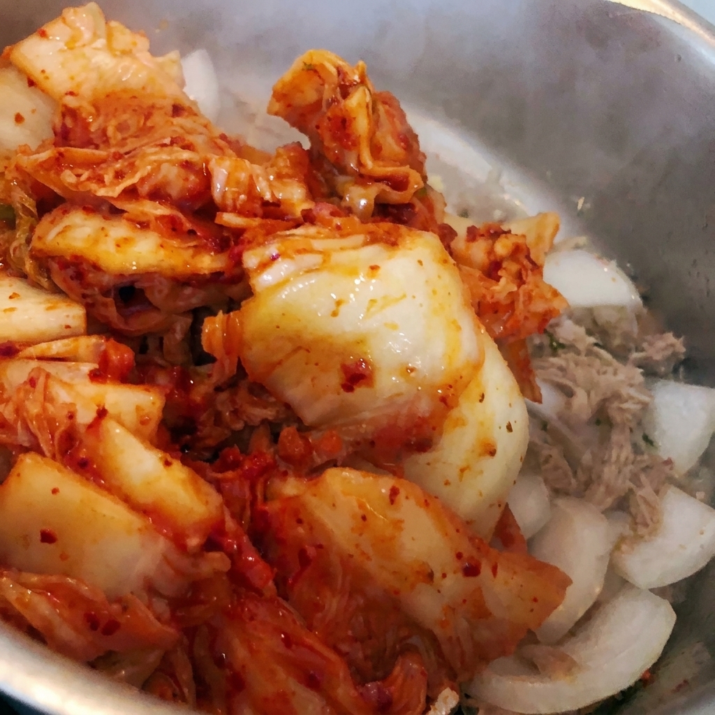 Posiekane kimchi wrzucane do garnka z istniejącymi składnikami.