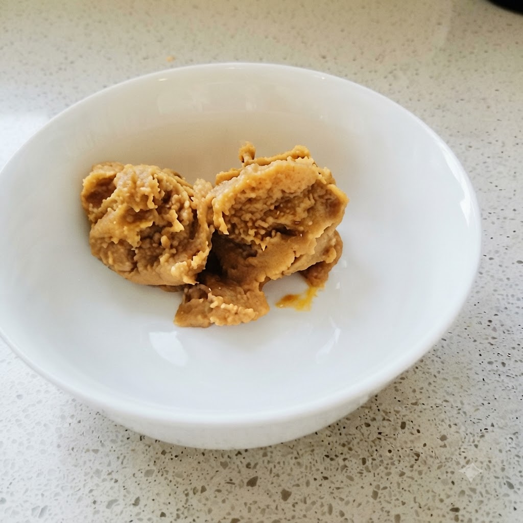Koreańska pasta sojowa i pasta chili dokładnie mieszane w białej misce złotą łyżką.