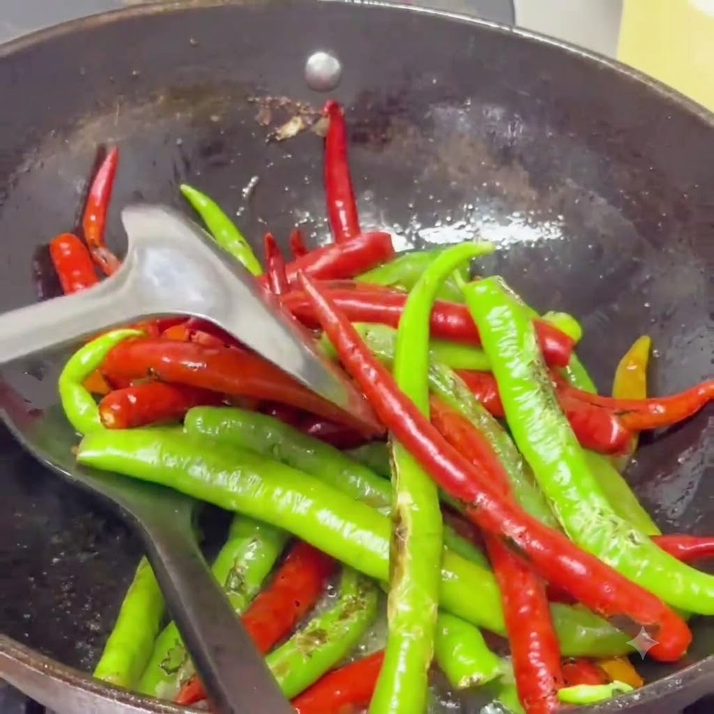 Przypieczone papryczki chili smażone metodą stir-fry za pomocą łopatki w woku wypełnionym mieniącym się aromatycznym olejem.