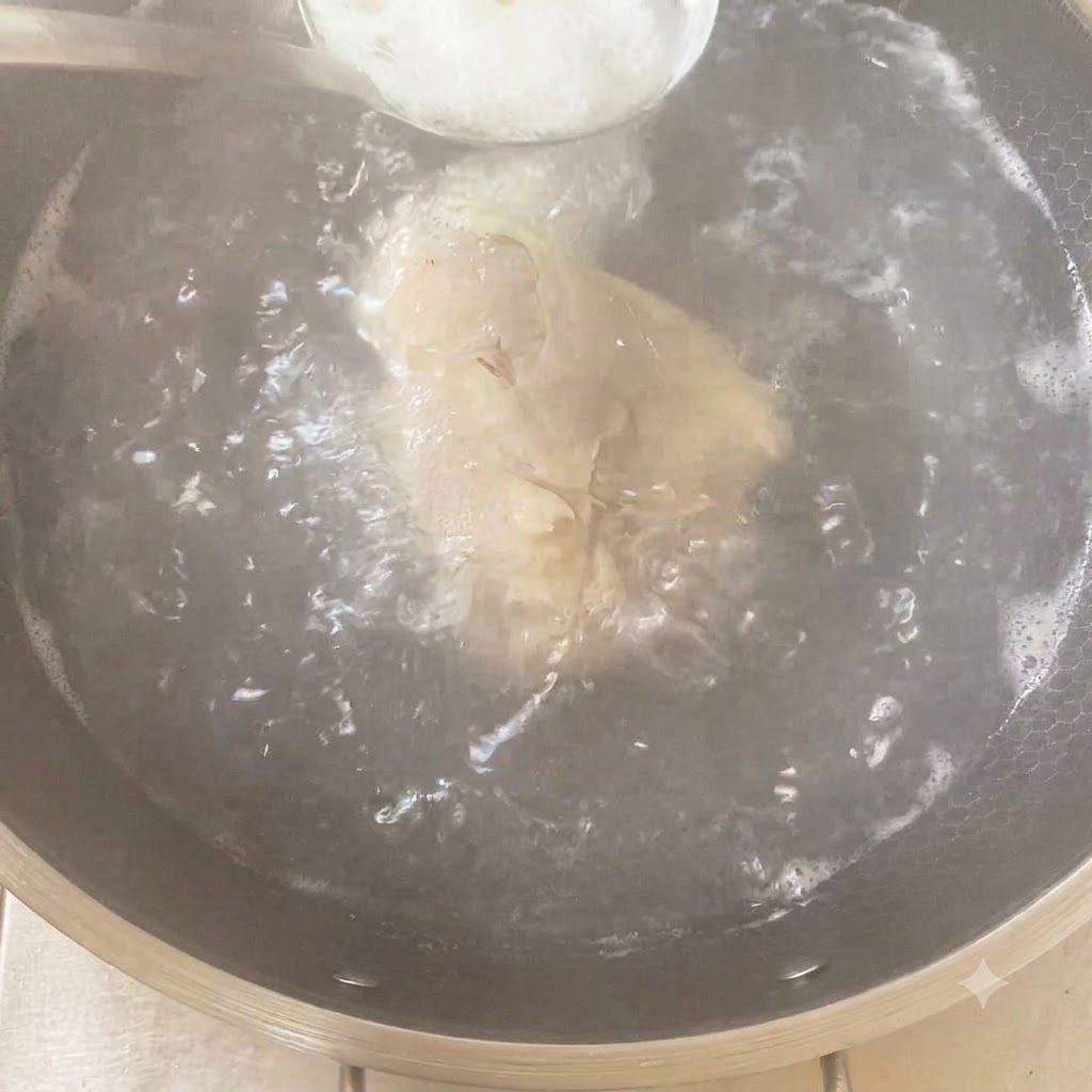 Łyżka przypraw dodawana do gotującego się garnka zawierającego kurczaka i aromaty.