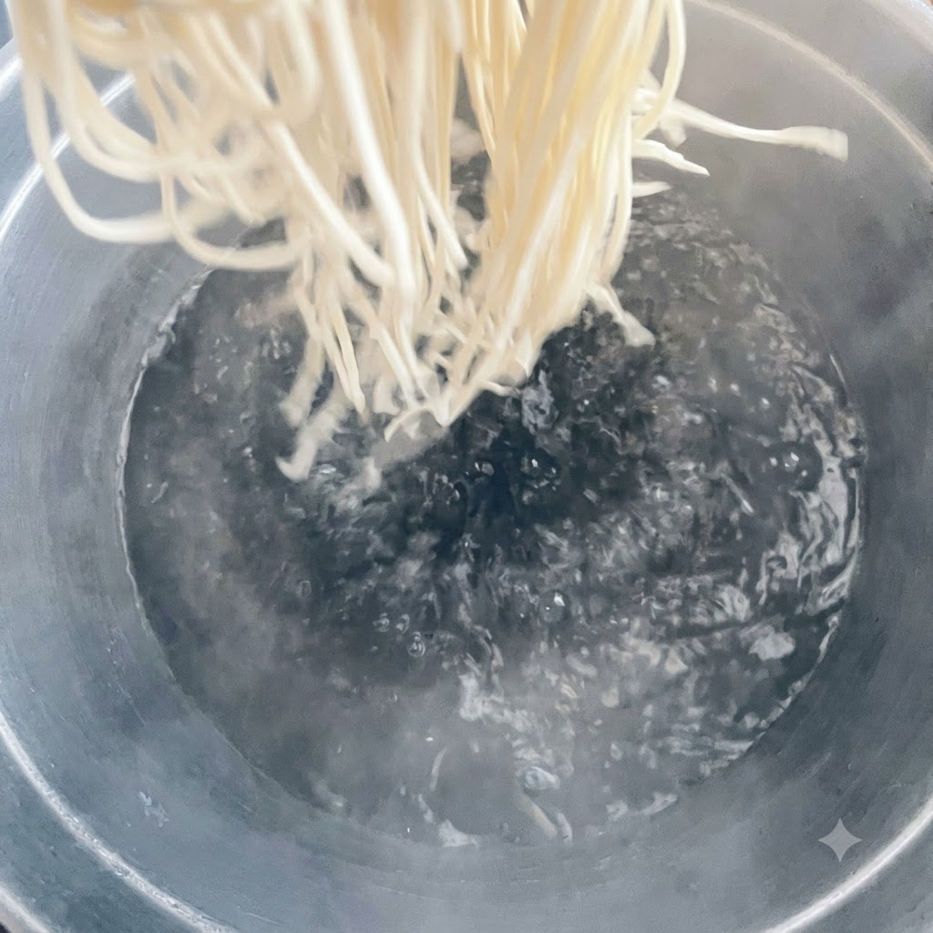 Makaron wrzucany do dużego garnka z gotującą się wodą.