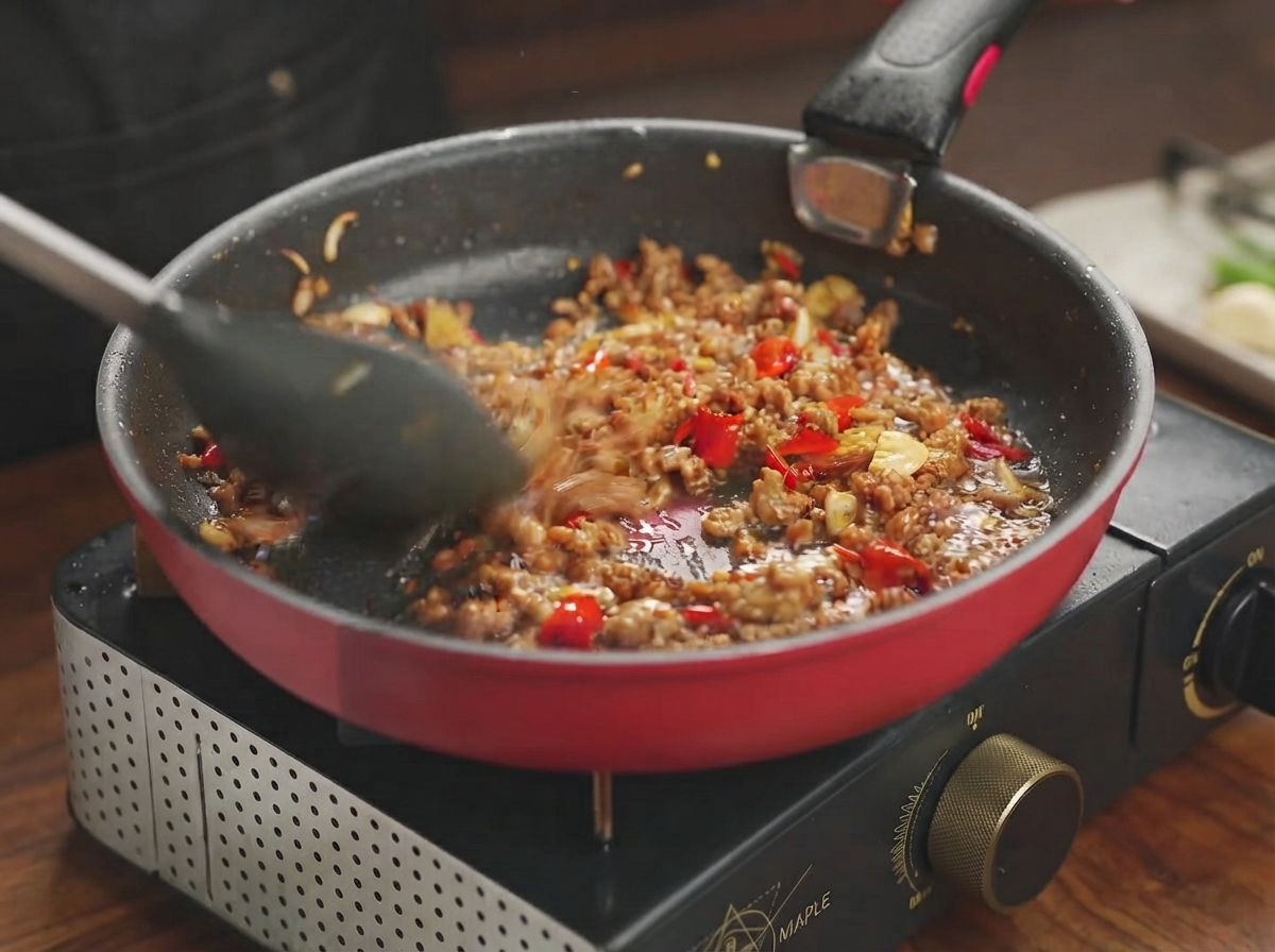 Mieszanka wieprzowa dusząca się i wchłaniająca esencjonalny sos na patelni.