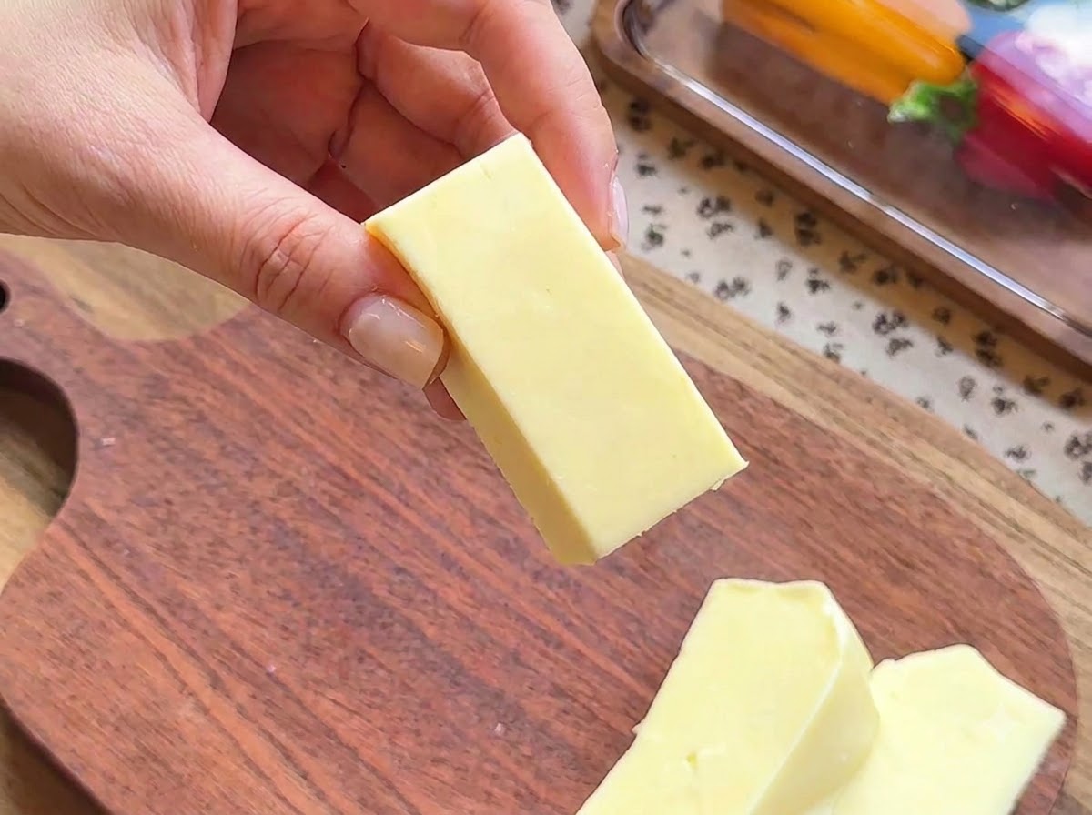 Zbliżenie dłoni trzymającej prostokątny blok sera mozzarella przygotowywany do nadziania.