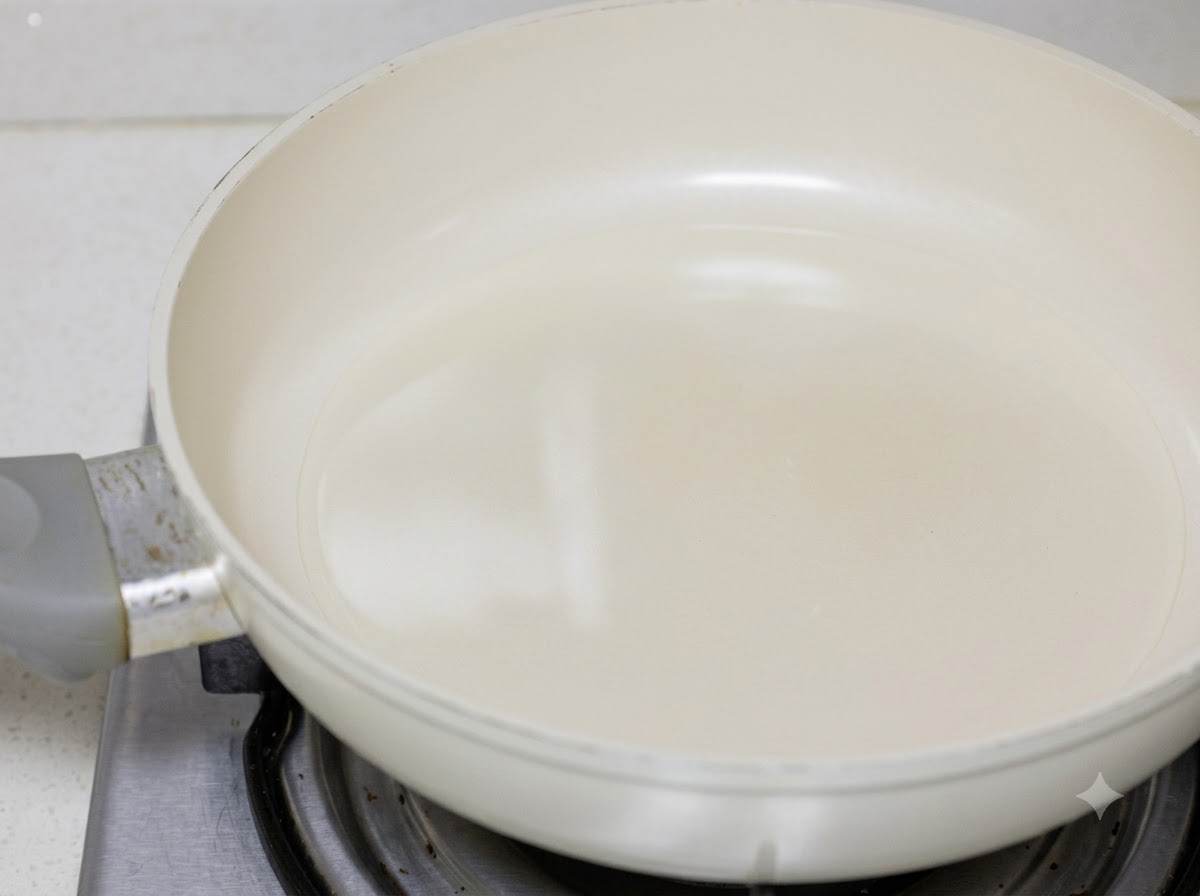 Kawałki kurczaka smażone na oleju w białej patelni wok.