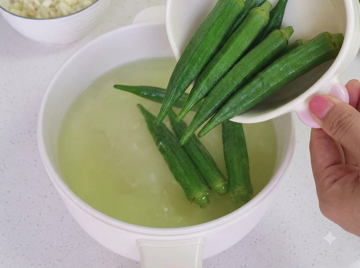 Ugotowana okra krojenia na małe kawałki na drewnianej desce do krojenia.