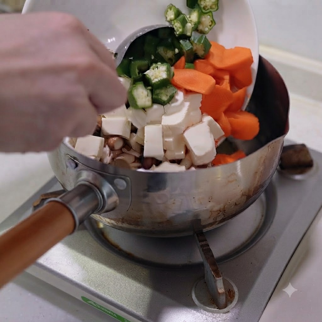 Posiekane warzywa i tofu przekładane z białego talerza do garnka ze stali nierdzewnej.