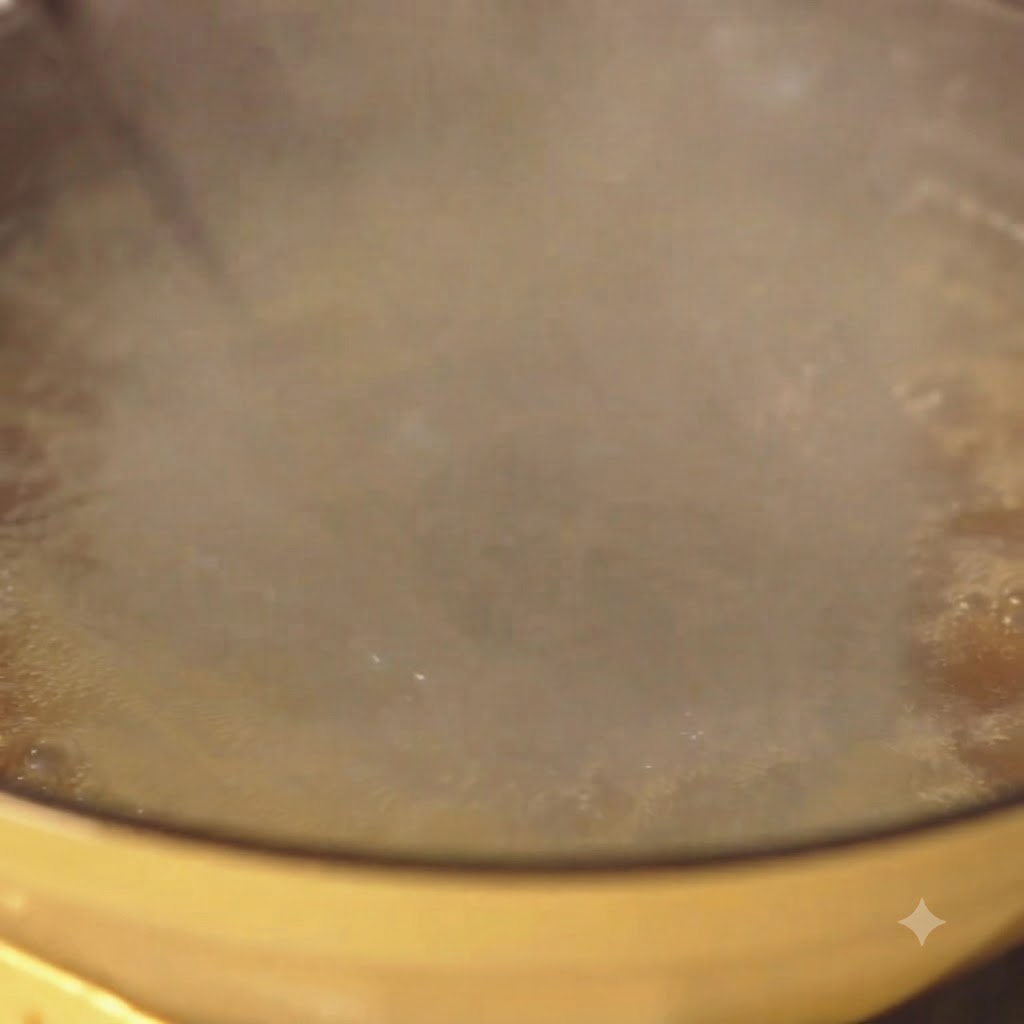 Spaghetti gotujące się intensywnie w żółtym garnku z wodą, nad którym unosi się para.