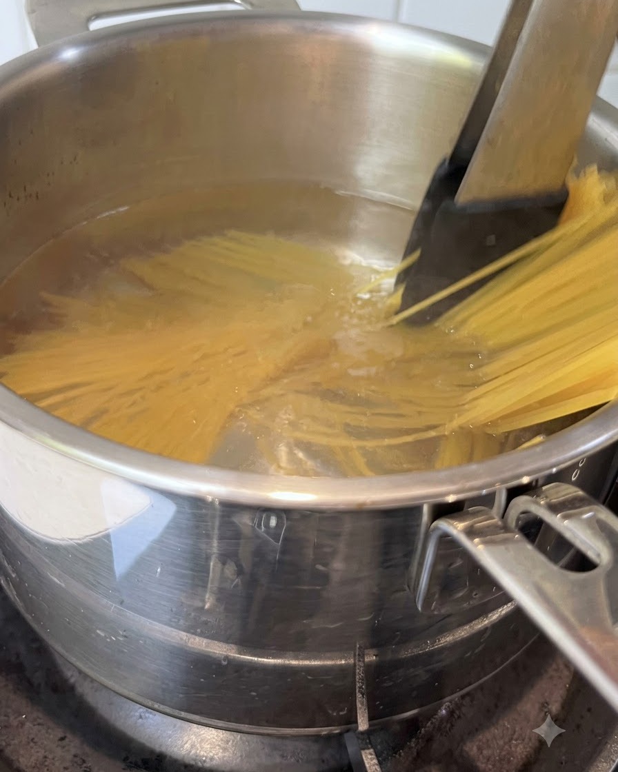 Makaron spaghetti mieszany szczypcami kuchennymi w garnku z wrzącą wodą.
