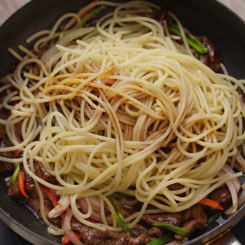 Sosy polewane na makaron spaghetti i wołowinę wewnątrz patelni.