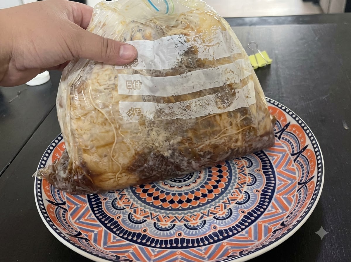 Dłoń trzymająca pakowaną próżniowo paczkę z mięsem leżącą na ozdobnym talerzu.