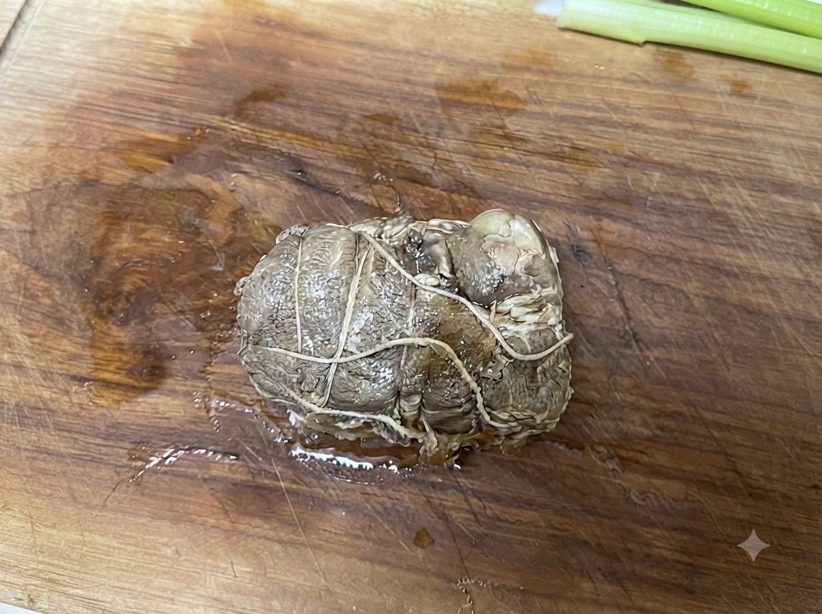 Związana zrolowana wieprzowina chashu leżąca na drewnianej desce do krojenia przed pokrojeniem.