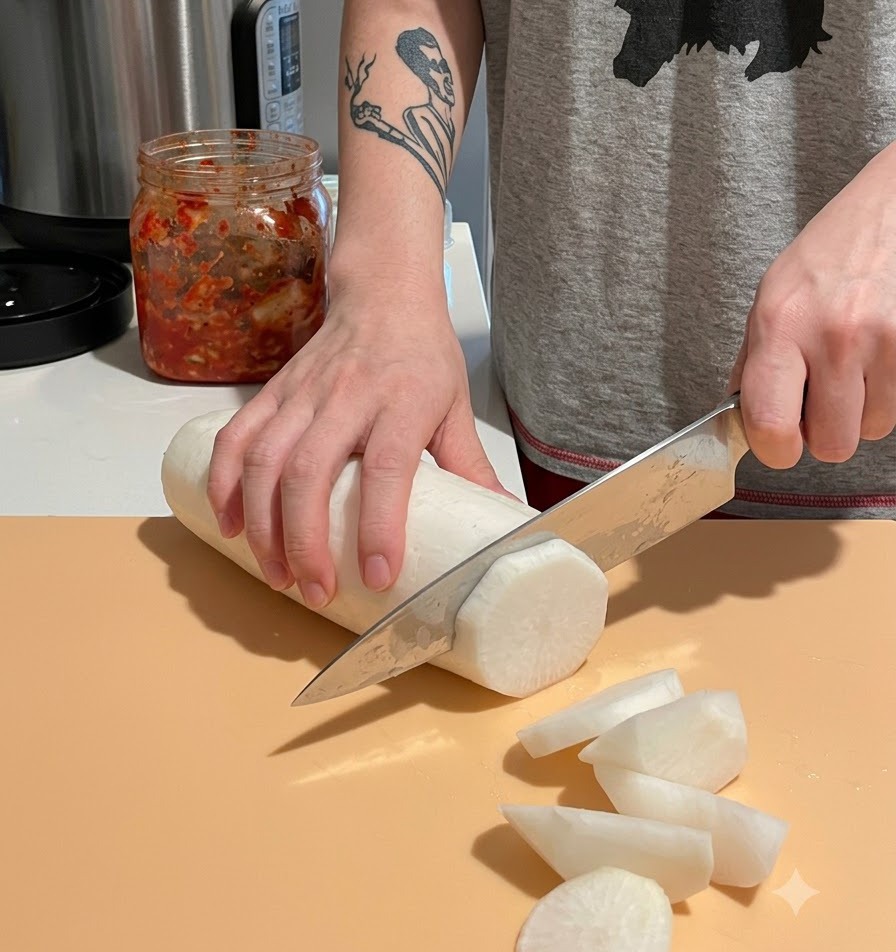 Krojenie obranej białej rzodkwi daikon na duże, grube kawałki na desce.