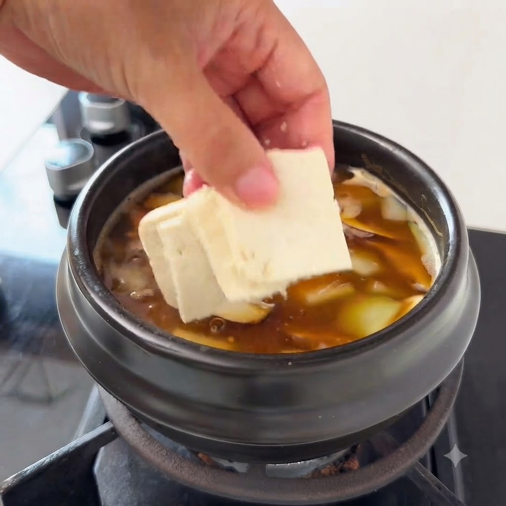 Kawałki tofu dodawane do zupy zawierającej plasterki cukinii i grzyby enoki.