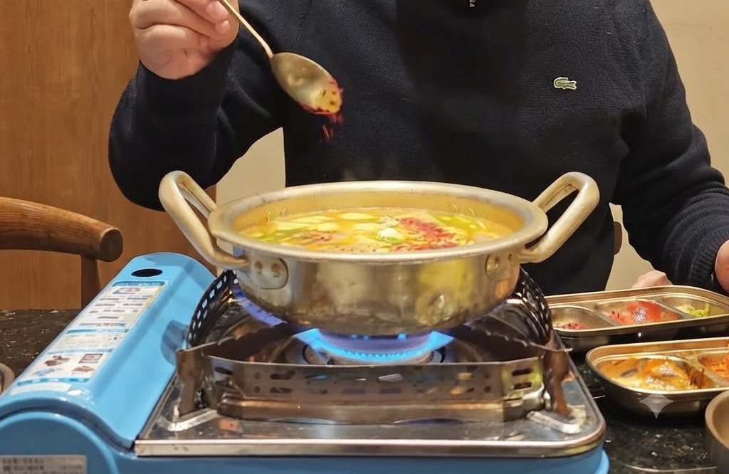 Łyżka czerwonego chili w proszku posypywana na bulgoczący garnek wypełniony warzywami i bulionem.