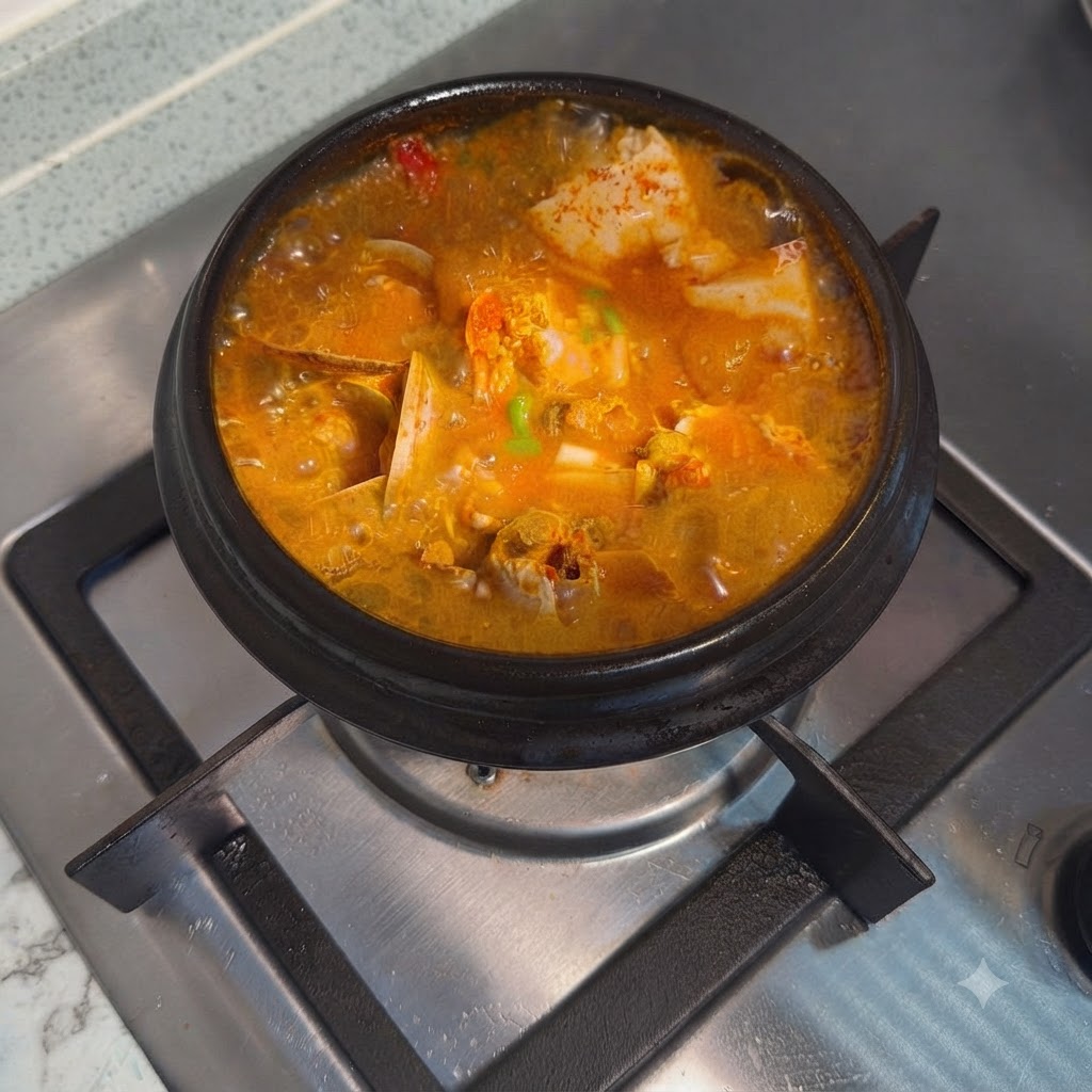 Gotowy koreański pikantny gulasz z miękkiego tofu przyozdobiony posiekaną zieloną cebulką w gorącym kamiennym garnku.