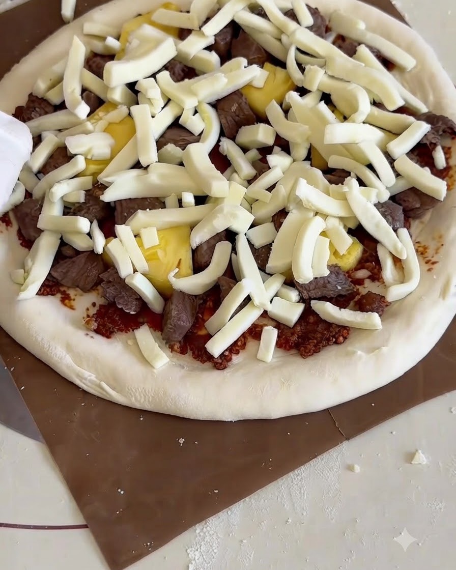 Surowa pizza zsuwana z drewnianej łopaty do nablatowego pieca na rozgrzany kamień.