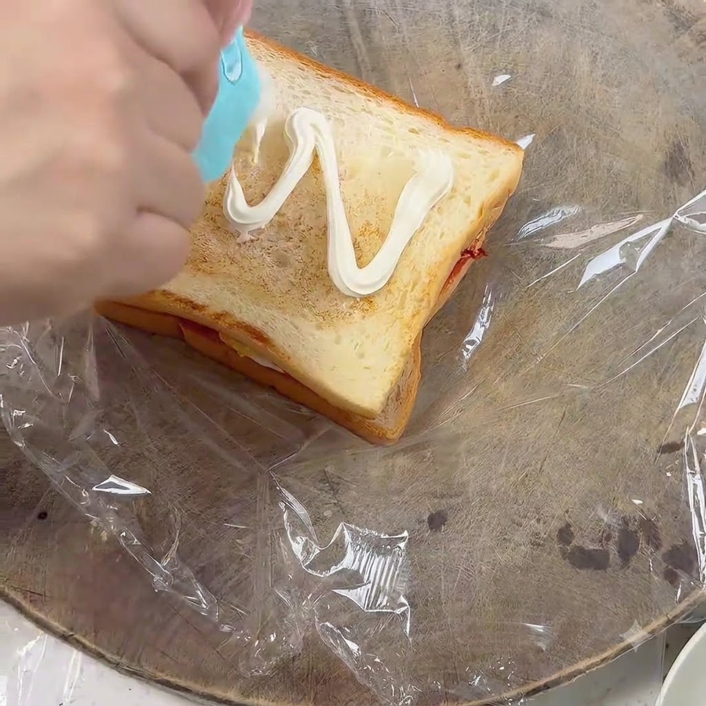 Wyciskanie majonezu zygzakiem na drugą kromkę opieczonego tosta.