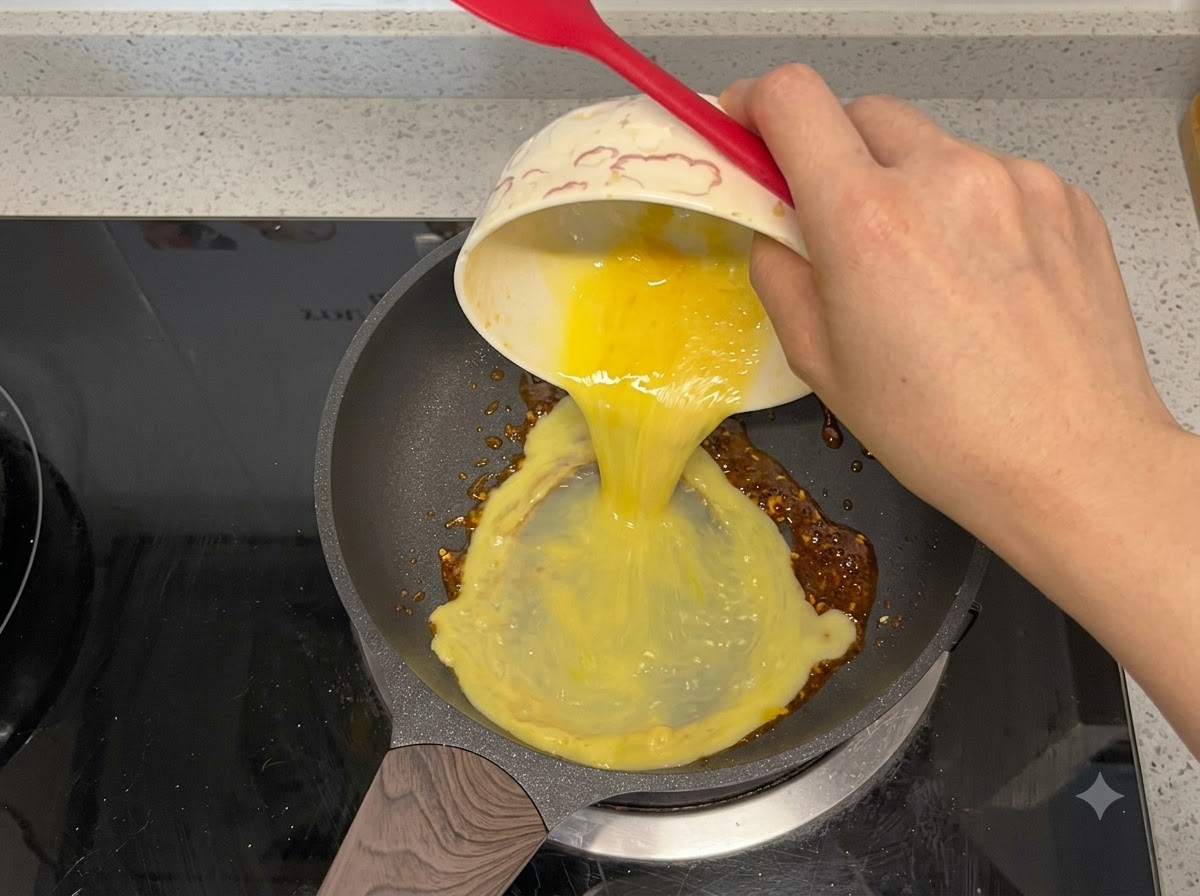 Ubijane jajka wlewane na patelnię z olejem chili.