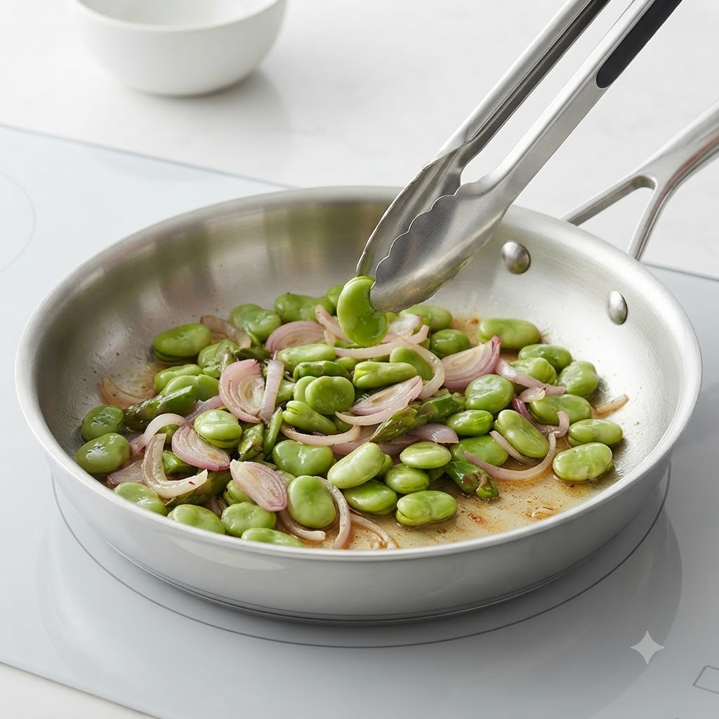 Pokrojona czerwona cebula, kawałki szparagów i bób smażone stir-fry na patelni ze stali nierdzewnej.