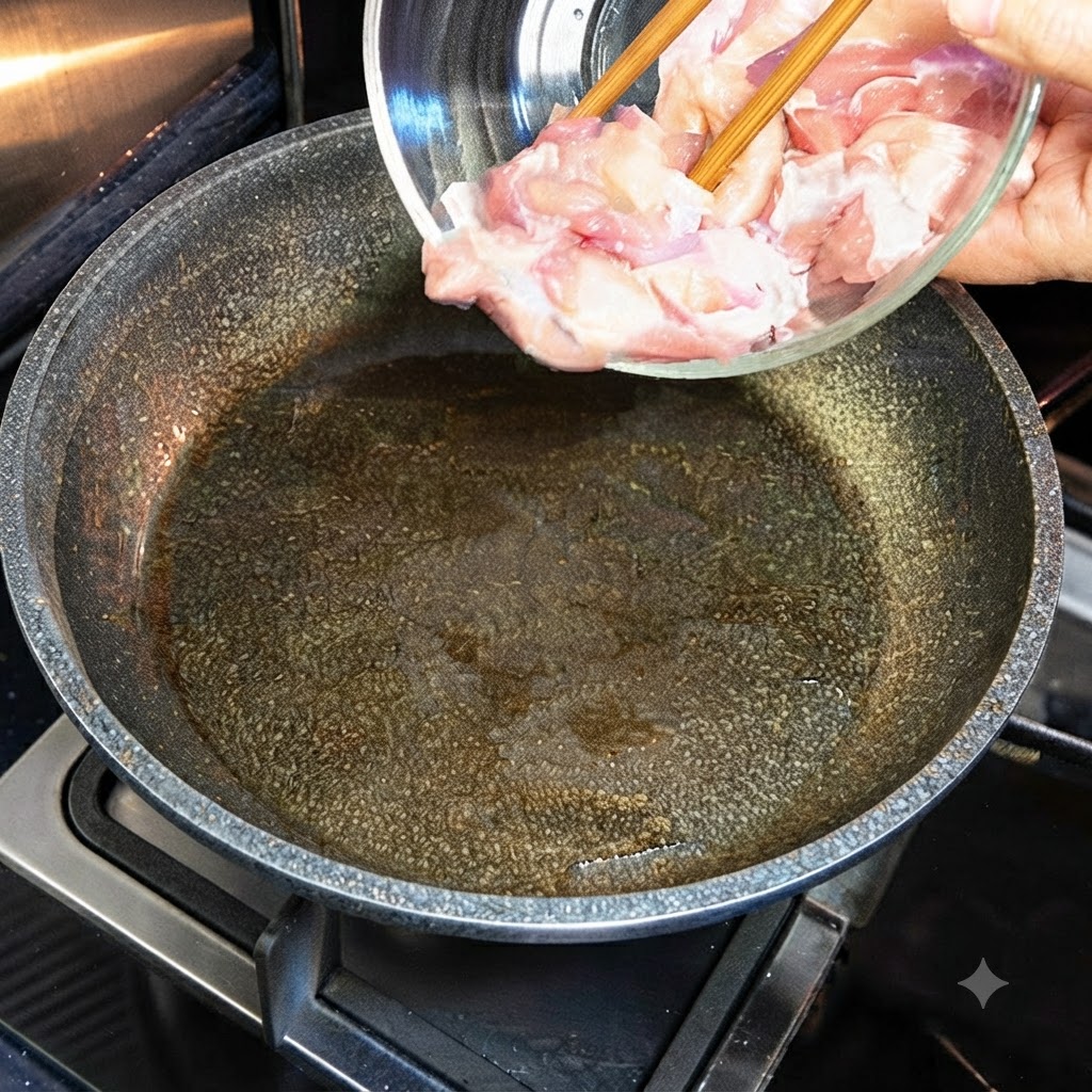 Surowe kawałki kurczaka przekładane ze szklanej miski na gorącą patelnię z olejem.
